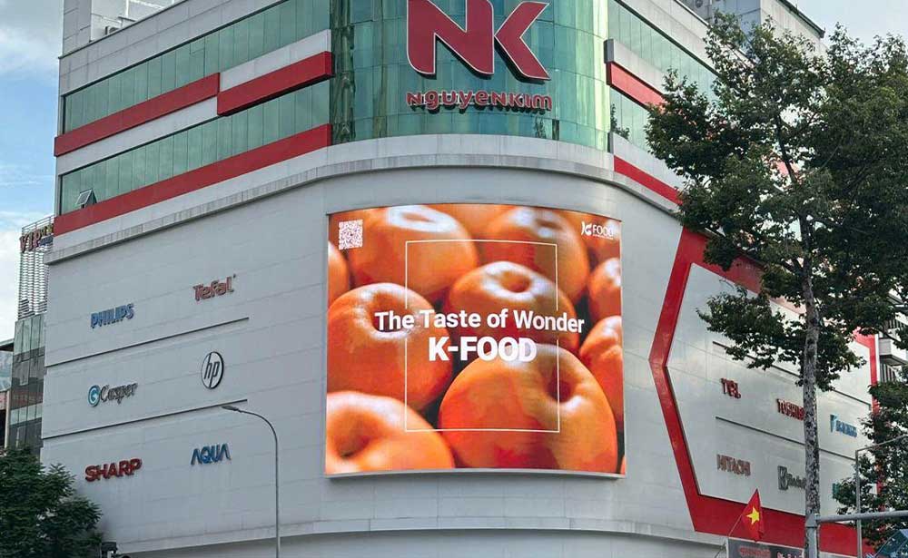 K-Food “The Taste of Wonder” campaign on a curved LED screen on the Nguyen Kim building, Ho Chi Minh City, Vietnam
