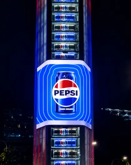 Pepsi campaign on a tall vertical LED screen lighting up a high-rise at night